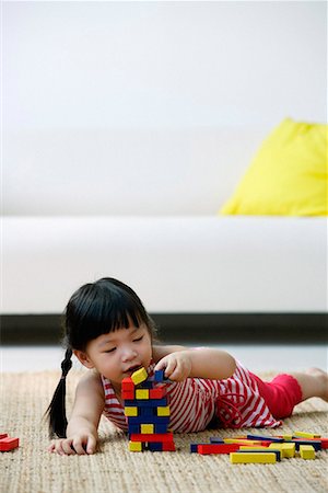 Une petite fille joue avec des blocs sur le sol Photographie de stock - Premium Libres de Droits, Code: 656-01766383