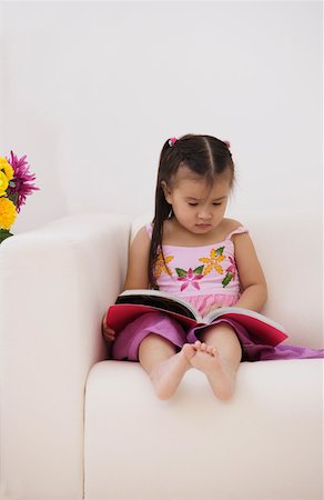 simsearch:656-01766387,k - Une jeune fille assise sur le canapé avec un livre Photographie de stock - Premium Libres de Droits, Code: 656-01766463