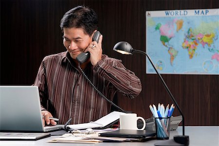 executive mentor - A man talks on the phone as he works Stock Photo - Premium Royalty-Free, Code: 656-01766475