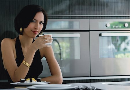 A woman looks at the camera as she holds a cup Stock Photo - Premium Royalty-Free, Code: 656-01766538