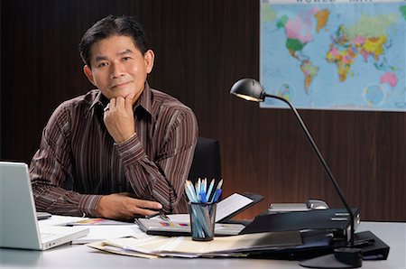 executive mentor - A man smiles at the camera as he sits at his desk Stock Photo - Premium Royalty-Free, Code: 656-01766608
