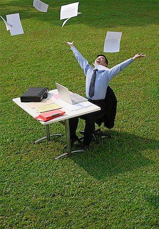 simsearch:656-02371640,k - Businessman sitting at desk and throwing paper in the air Foto de stock - Sin royalties Premium, Código: 656-01766992