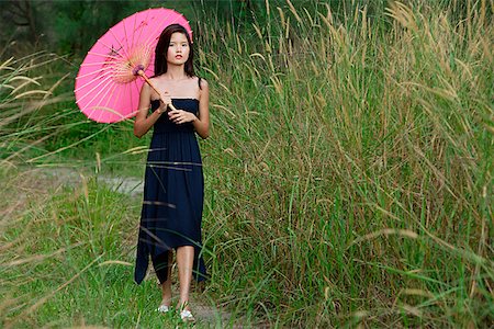 Femme qui marche dans l'herbe longue avec parasol Photographie de stock - Premium Libres de Droits, Code: 656-01767044