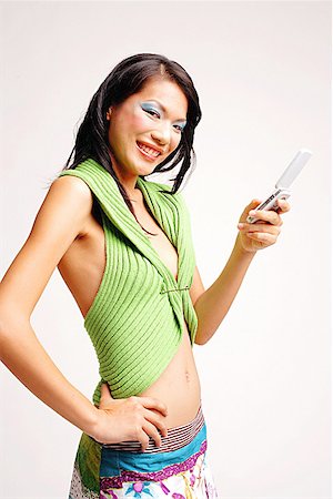 singapore women 30s - Young woman with mobile phone, hand on hip, smiling at camera Stock Photo - Premium Royalty-Free, Code: 656-01767277