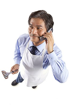 simsearch:656-03519571,k - Mature man wearing apron, holding spatula and using mobile phone Foto de stock - Sin royalties Premium, Código: 656-01767594