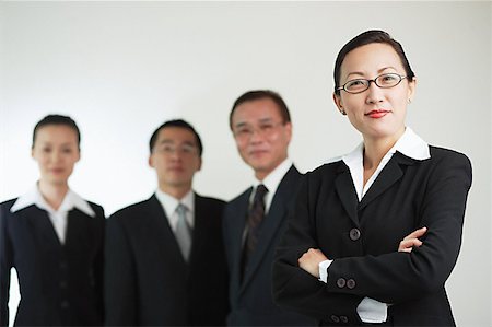 simsearch:656-01767698,k - Businesswoman with arms crossed, other executives in the background Foto de stock - Royalty Free Premium, Número: 656-01767646