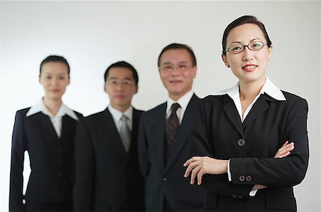 simsearch:656-01767698,k - Businesswoman with arms crossed, other executives in the background Foto de stock - Royalty Free Premium, Número: 656-01767648