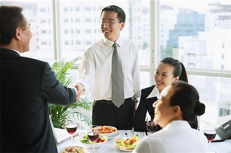 simsearch:656-01767698,k - Businessmen shaking hands over lunch table, businesswomen sitting next to them Foto de stock - Royalty Free Premium, Número: 656-01767708