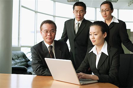 Woman using laptop, other executives around her watching Stock Photo - Premium Royalty-Free, Code: 656-01767717