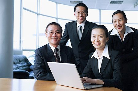 simsearch:656-01767698,k - Executives looking at camera, laptop open in front of them Foto de stock - Royalty Free Premium, Número: 656-01767718