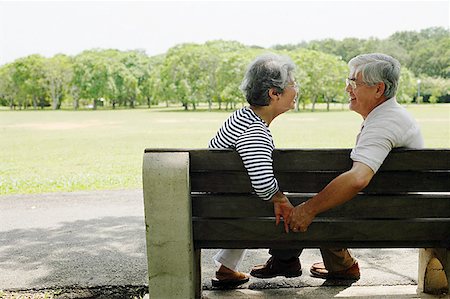 Mature couple sitting face to face on park bench, holding hands Stock Photo - Premium Royalty-Free, Code: 656-01767773