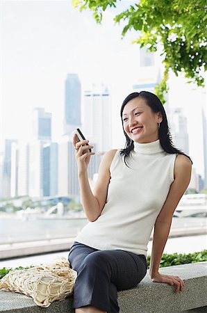 singapore women 30s - Young woman, looking at mobile phone, smiling Stock Photo - Premium Royalty-Free, Code: 656-01767792