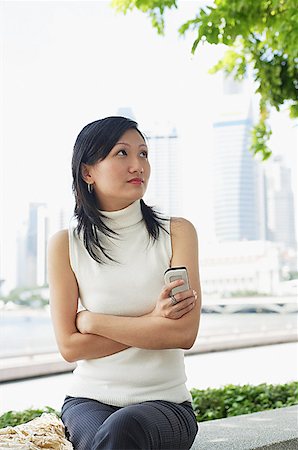 simsearch:656-01773928,k - Young woman, holding mobile phone arms crossed Foto de stock - Royalty Free Premium, Número: 656-01767793