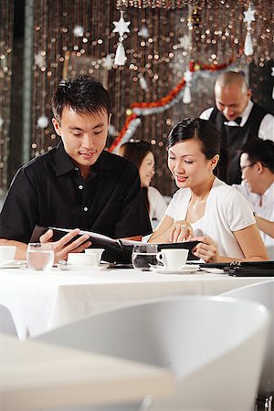 simsearch:656-01767905,k - Couple in restaurant, looking through menu, people in the background Fotografie stock - Premium Royalty-Free, Codice: 656-01767840