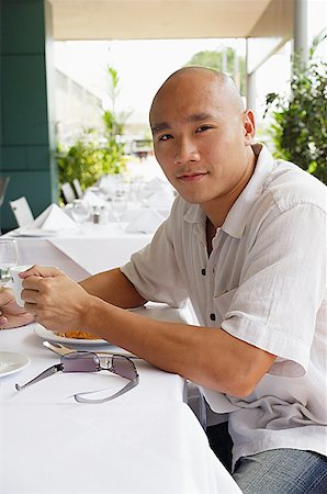 sunglasses for bald men - Man sitting at table, holding cup looking at camera Stock Photo - Premium Royalty-Free, Code: 656-01767857