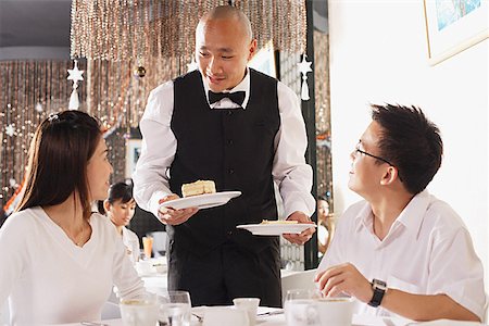 simsearch:656-01771940,k - Couple in restaurant, waiter standing, holding plates of dessert Fotografie stock - Premium Royalty-Free, Codice: 656-01767904