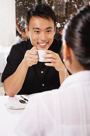 simsearch:656-01767905,k - Couple eating in restaurant, man holding cup, over the shoulder view Fotografie stock - Premium Royalty-Free, Codice: 656-01767918