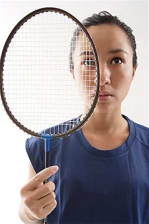 Woman holding badminton racket next to her face Stock Photo - Premium Royalty-Free, Code: 656-01767955