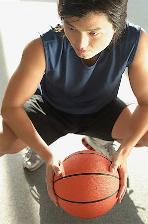 simsearch:656-01767934,k - Man crouching, holding basketball looking away Foto de stock - Sin royalties Premium, Código: 656-01767985