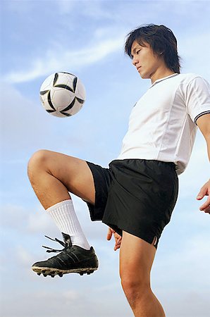 simsearch:656-01767934,k - Man bouncing soccer ball on knee Foto de stock - Sin royalties Premium, Código: 656-01767998