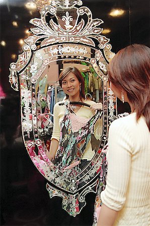 simsearch:656-01773354,k - Woman in clothing store, holding dress, looking at mirror Foto de stock - Sin royalties Premium, Código: 656-01768015