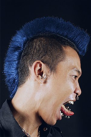 Man with mohawk, side view, mouth open, sticking tongue out Foto de stock - Royalty Free Premium, Número: 656-01768017