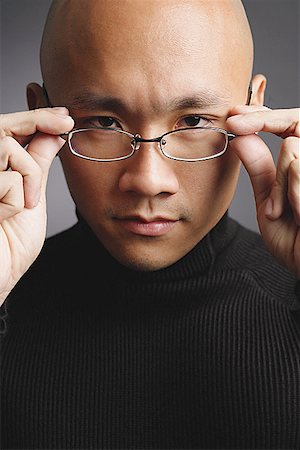 eyeglasses for bald heads - Man with shaved head, adjusting glasses, looking at camera Stock Photo - Premium Royalty-Free, Code: 656-01768032