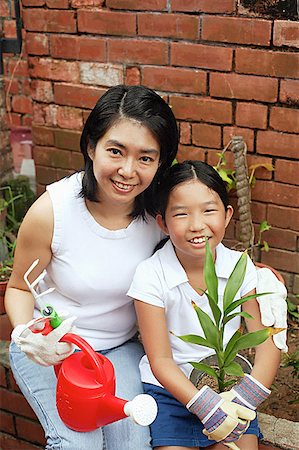 simsearch:656-01768177,k - Mother and daughter, sitting in garden, holding plant and watering can Stock Photo - Premium Royalty-Free, Code: 656-01768175