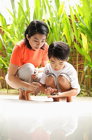 Mother and son crouching, son holding terrapin Stock Photo - Premium Royalty-Free, Code: 656-01768221