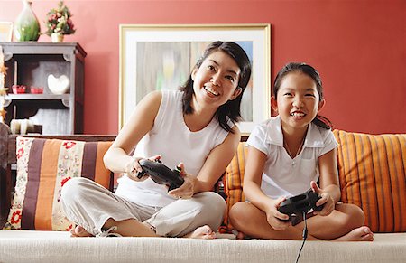 simsearch:656-01768260,k - Mother and daughter in living room, playing video game Fotografie stock - Premium Royalty-Free, Codice: 656-01768232