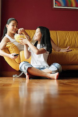 parquetry - Two sisters sitting in living room, eating popcorn Stock Photo - Premium Royalty-Free, Code: 656-01768244