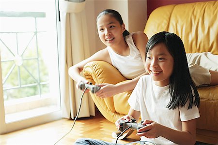 simsearch:656-01770739,k - Two sisters in living room, playing video games Fotografie stock - Premium Royalty-Free, Codice: 656-01768248
