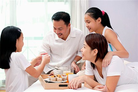 simsearch:656-01768333,k - Family of four in bedroom, breakfast tray on the bed next to them Stock Photo - Premium Royalty-Free, Code: 656-01768316