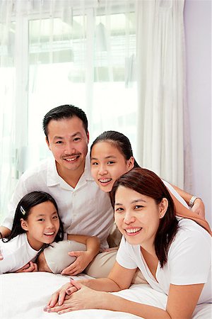 preteen asian girls bed - Family of four in smiling at camera Stock Photo - Premium Royalty-Free, Code: 656-01768319