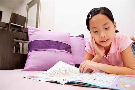 preteen asian girls bed - Girl reading magazine, lying on front, hand on chin Stock Photo - Premium Royalty-Free, Code: 656-01768332