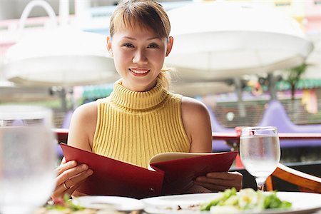 eating out - Woman holding menu, looking at camera, smiling Stock Photo - Premium Royalty-Free, Code: 656-01768445