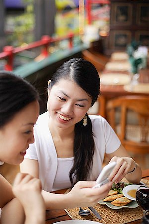 dining out friends - Women sitting in cafe, looking at mobile phone Stock Photo - Premium Royalty-Free, Code: 656-01768473