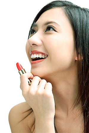 profile woman head and shoulders one person studio shot side view looking away - Woman smiling looking away, holding lipstick Stock Photo - Premium Royalty-Free, Code: 656-01768514