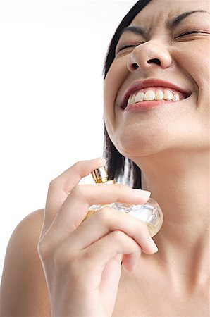 Woman holding perfume bottle, eyes closed, smiling Stock Photo - Premium Royalty-Free, Code: 656-01768601