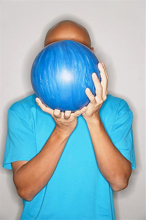 einzelgänger (männlich und weiblich) - Mann, der Bowling-Kugel vor Gesicht Stockbilder - Premium RF Lizenzfrei, Bildnummer: 656-01768689