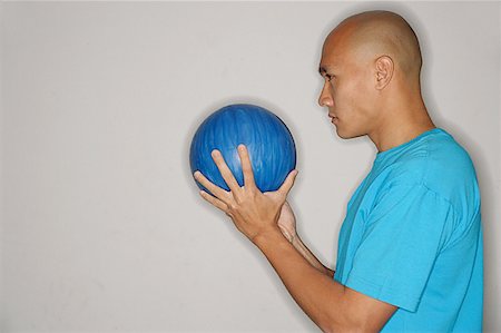 shaved head profile asian - Man holding bowling ball in front of face, looking away Stock Photo - Premium Royalty-Free, Code: 656-01768701