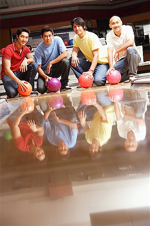 simsearch:656-01768686,k - Quatre hommes dans la salle de quilles, accroupi, tenant des boules de bowling Photographie de stock - Premium Libres de Droits, Code: 656-01768735