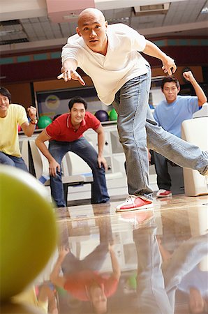 Man bowling, friends in the background, cheering Stock Photo - Premium Royalty-Free, Code: 656-01768732