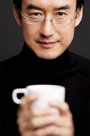 Man with glasses, holding mug, black background Stock Photo - Premium Royalty-Free, Code: 656-01768757
