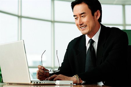 simsearch:656-03519571,k - Businessman in office looking at laptop, smiling Foto de stock - Sin royalties Premium, Código: 656-01768765