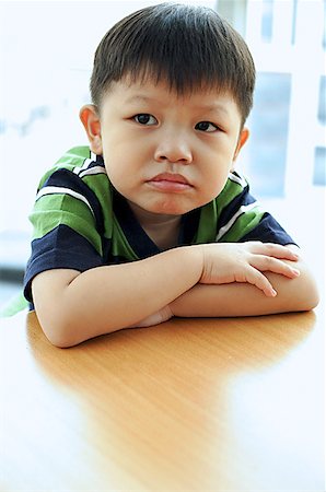 Young boy looking away, arms crossed, leaning on table Stock Photo - Premium Royalty-Free, Code: 656-01768811