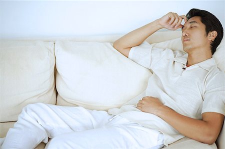 eyes closed portrait of asian man - Man lying on sofa, sleeping, hand on head Stock Photo - Premium Royalty-Free, Code: 656-01769042