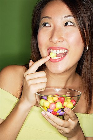 simsearch:656-01771940,k - Woman with bowl of candy, putting candy into mouth Foto de stock - Sin royalties Premium, Código: 656-01769394