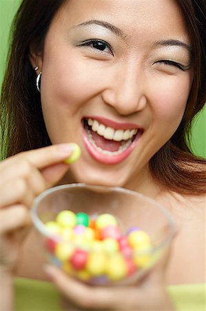 simsearch:656-01771940,k - Woman holding candy and candy bowl, winking Fotografie stock - Premium Royalty-Free, Codice: 656-01769414