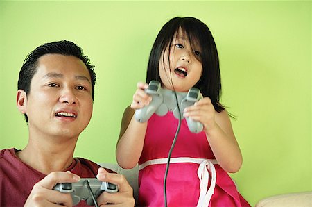 simsearch:656-01770739,k - Father and daughter, side by side playing video games Fotografie stock - Premium Royalty-Free, Codice: 656-01769490